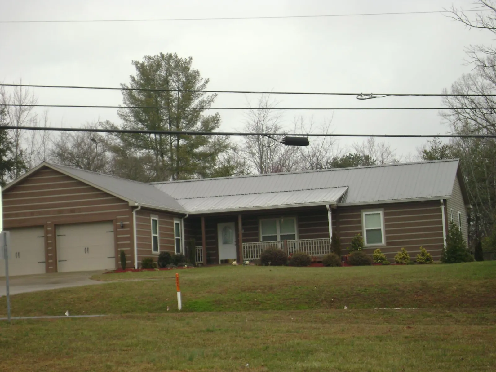 Gray metal roof on a log sided ranch home with a front porch in Conway